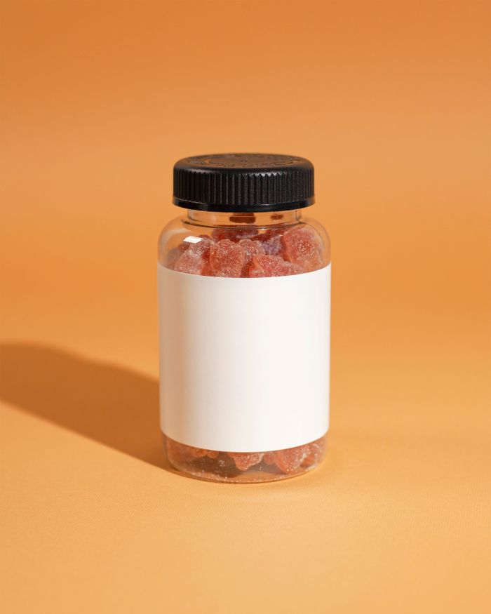 about-02 Close-up of a clear supplement bottle with gummies against an orange background.
