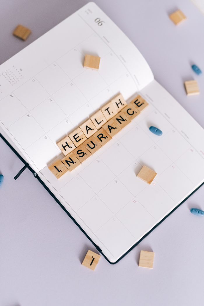 Crafting Captivating Headlines: Your awesome post title goes here Flat lay of planner with 'Health Insurance' in Scrabble tiles, emphasizing planning and health.